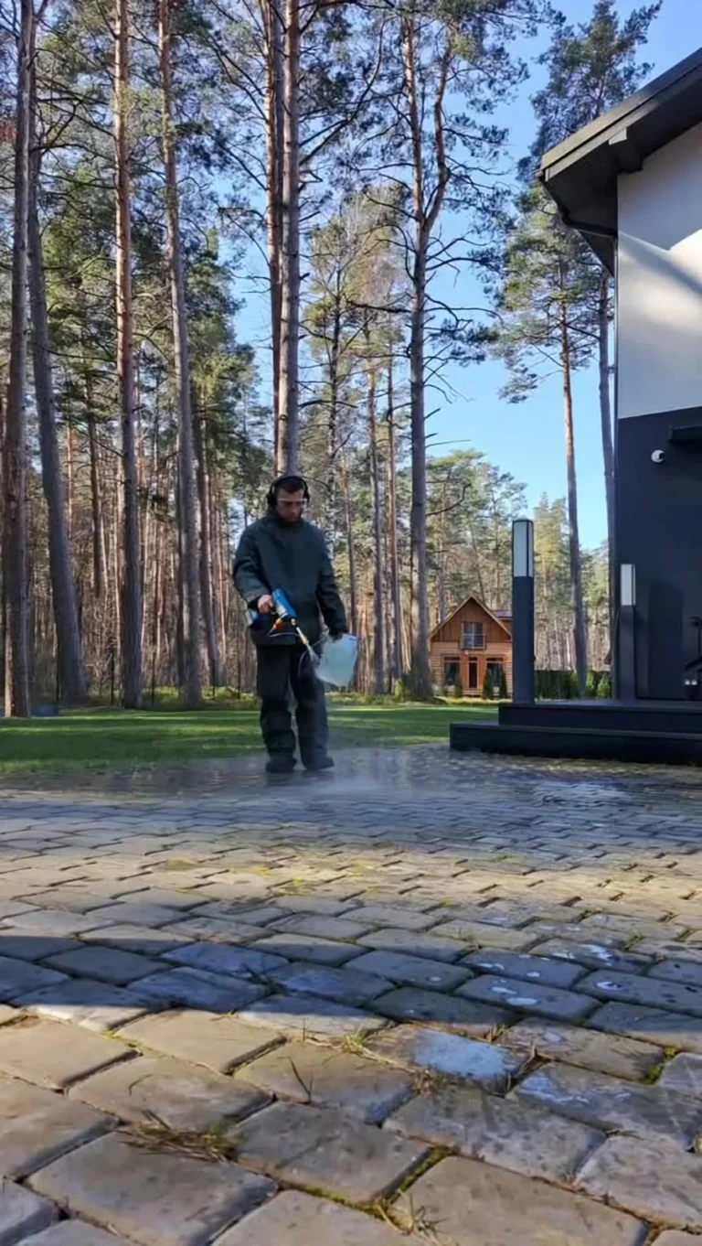 AMBRU darbinieks tīra bruģakmens segumu privātmājas pagalmā